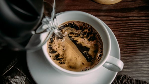 Foto de uma caneca de cerâmica branca com café solúvel sendo feito